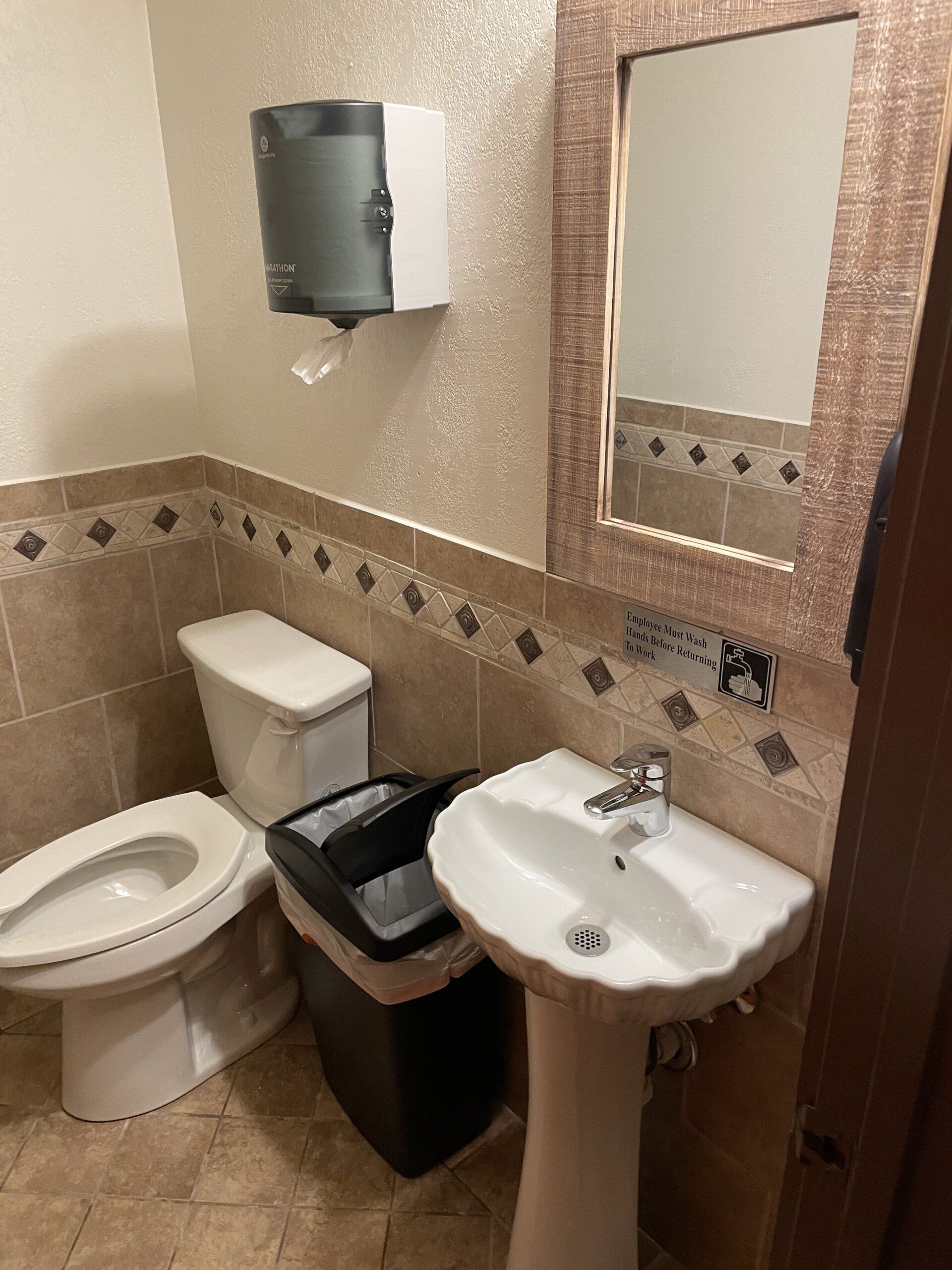 A bathroom with a toilet , sink and mirror