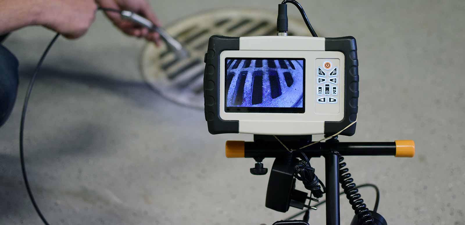 A man is using a camera to look at a manhole cover.