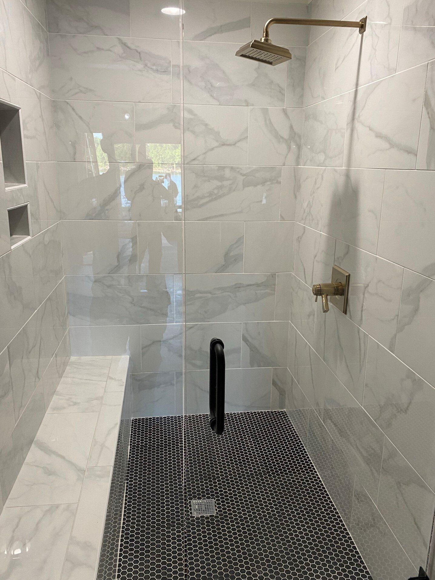 A bathroom with a walk in shower and a bench.