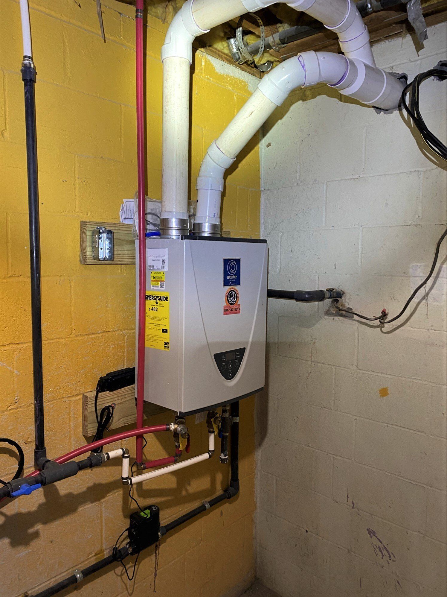 A water heater is hanging from the ceiling in a basement.