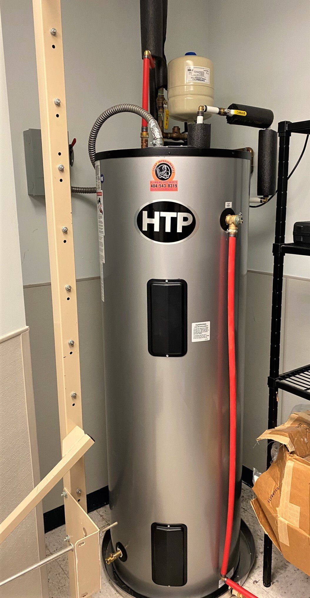 A stainless steel water heater is sitting on the floor in a room.