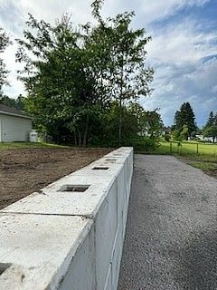 Un mur de béton est en cours de construction à côté d'une route de gravier.