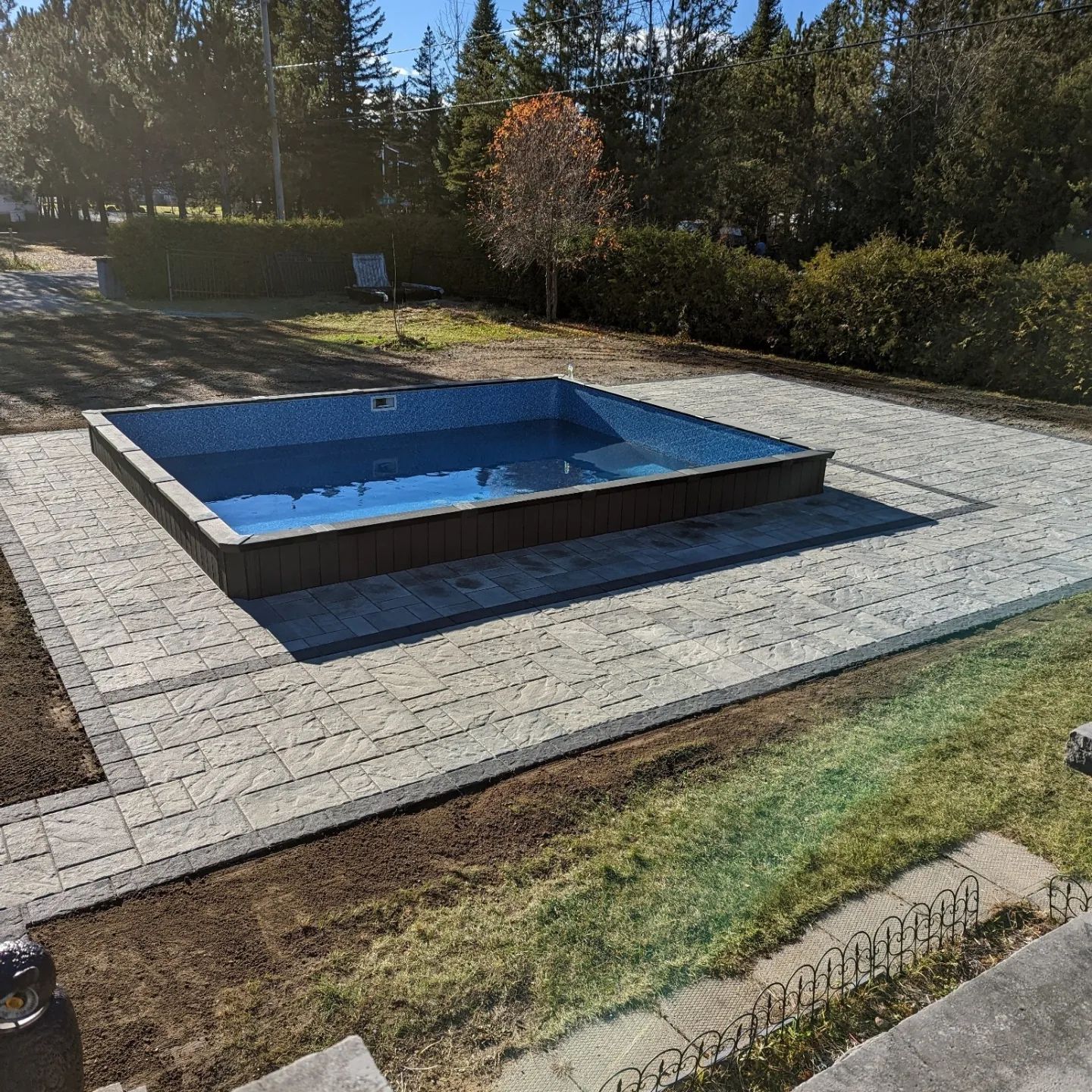 Une grande piscine se trouve au sommet d'un patio en brique.
