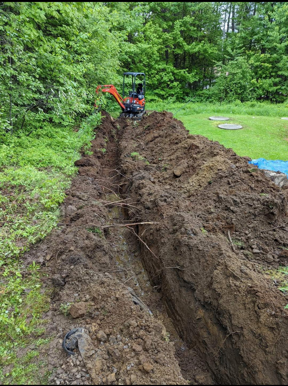 Une petite excavatrice creuse une tranchée dans la terre.