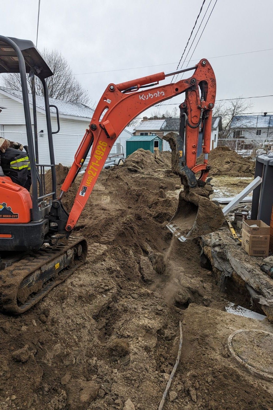 Une petite excavatrice creuse un trou dans le sol.