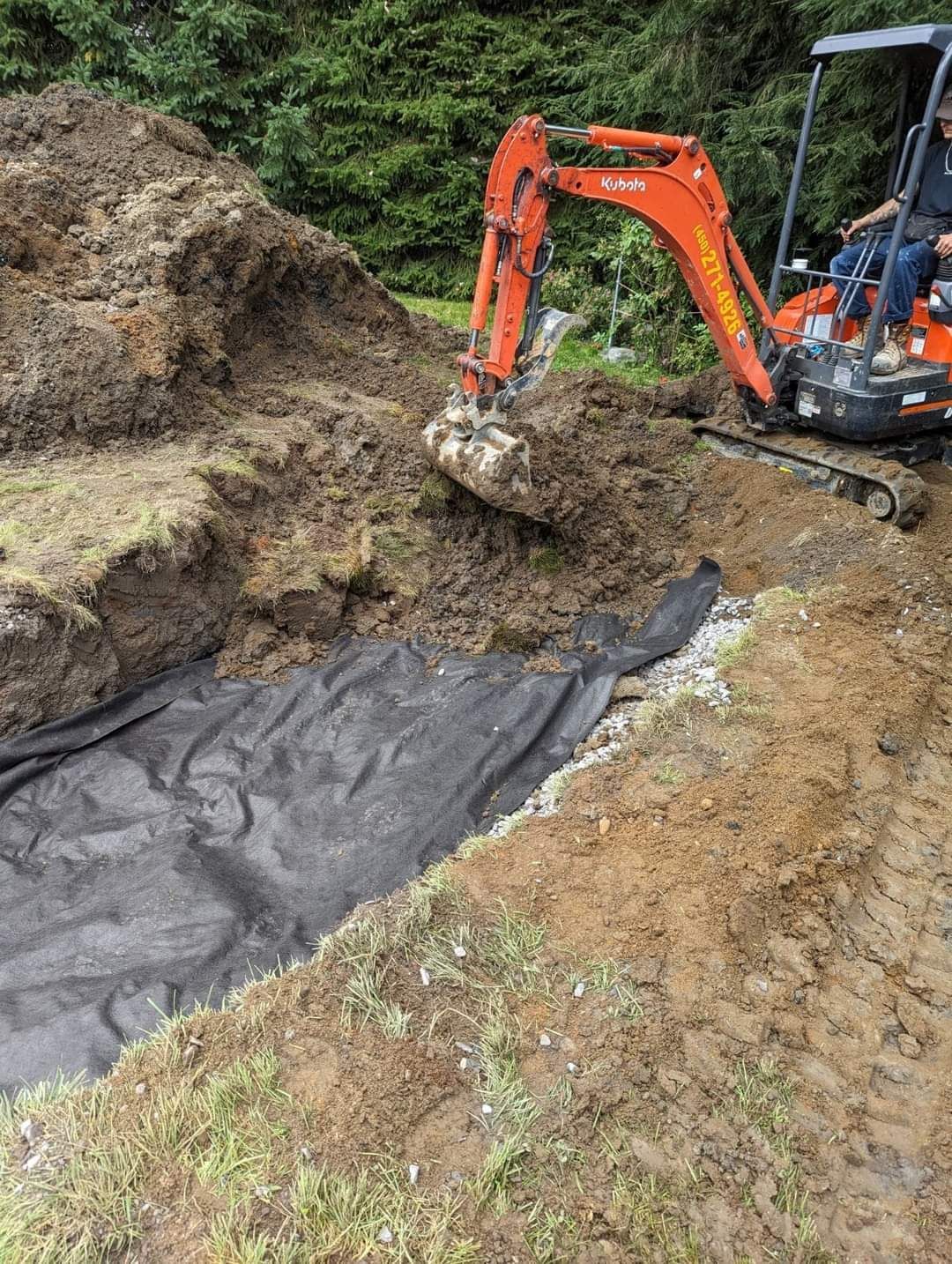 Un homme conduit une excavatrice sur un chemin de terre.