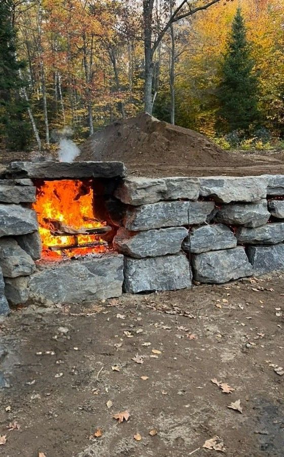 Un foyer est construit dans un mur de pierre dans les bois.