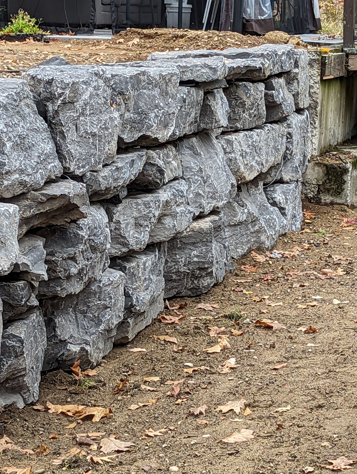 Une grande paroi rocheuse se trouve au sommet d'un champ de terre.