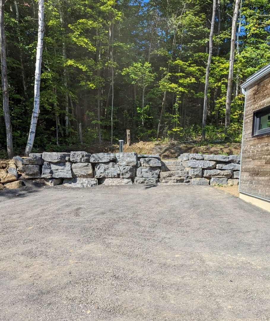 Il y a un mur de pierre au milieu des bois.