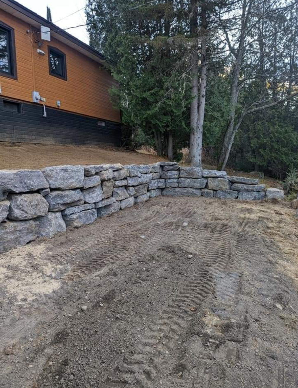 Un mur de pierre est en construction devant une maison.