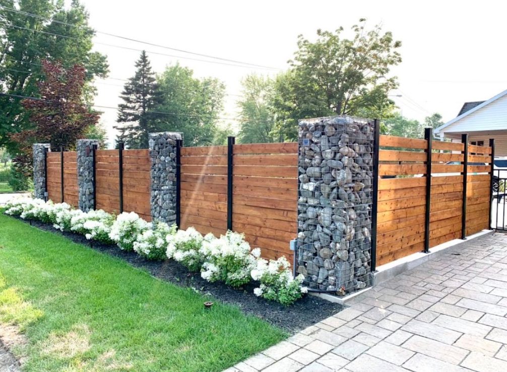 Une clôture en bois avec des rochers devant une maison.
