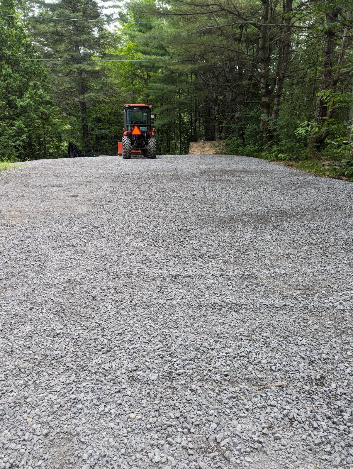 Un tracteur roule sur une route de gravier.