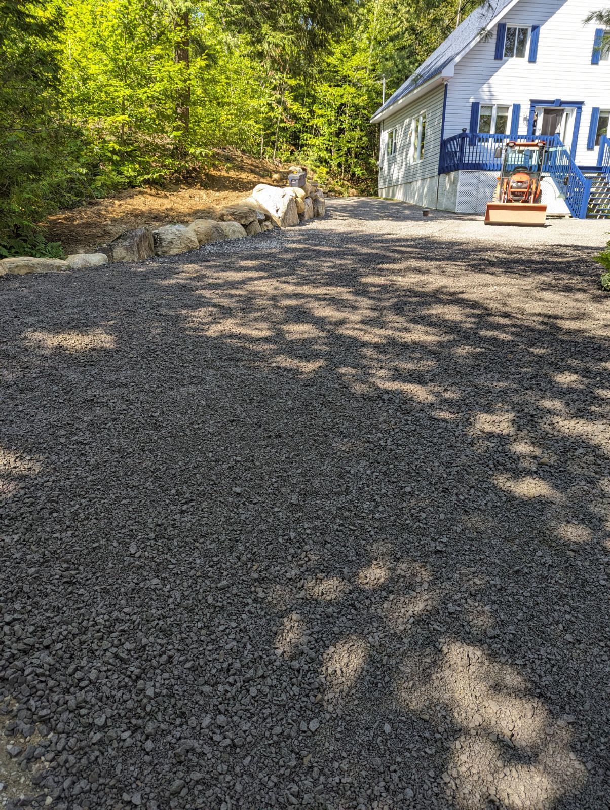 Une allée de gravier menant à une maison dans les bois.
