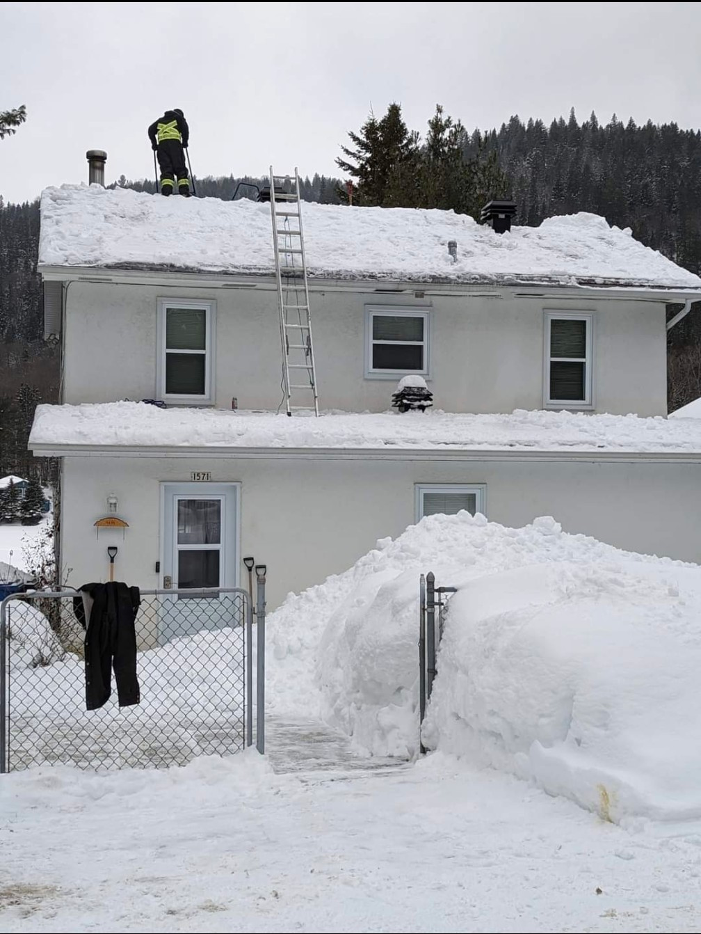 Une maison enneigée avec une échelle sur le toit
