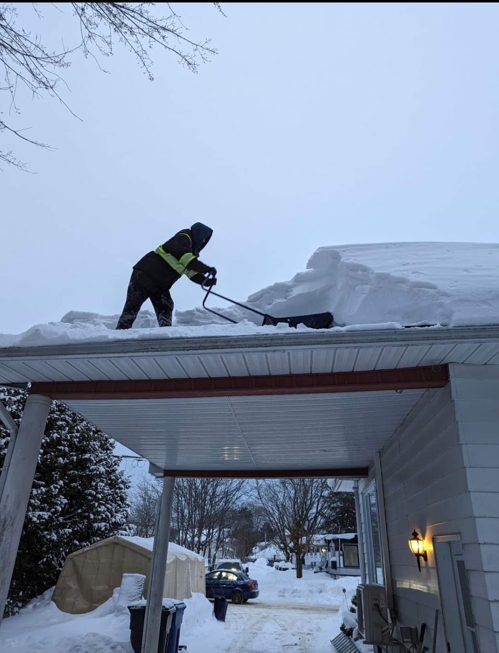 Un homme déneige le toit d'une maison