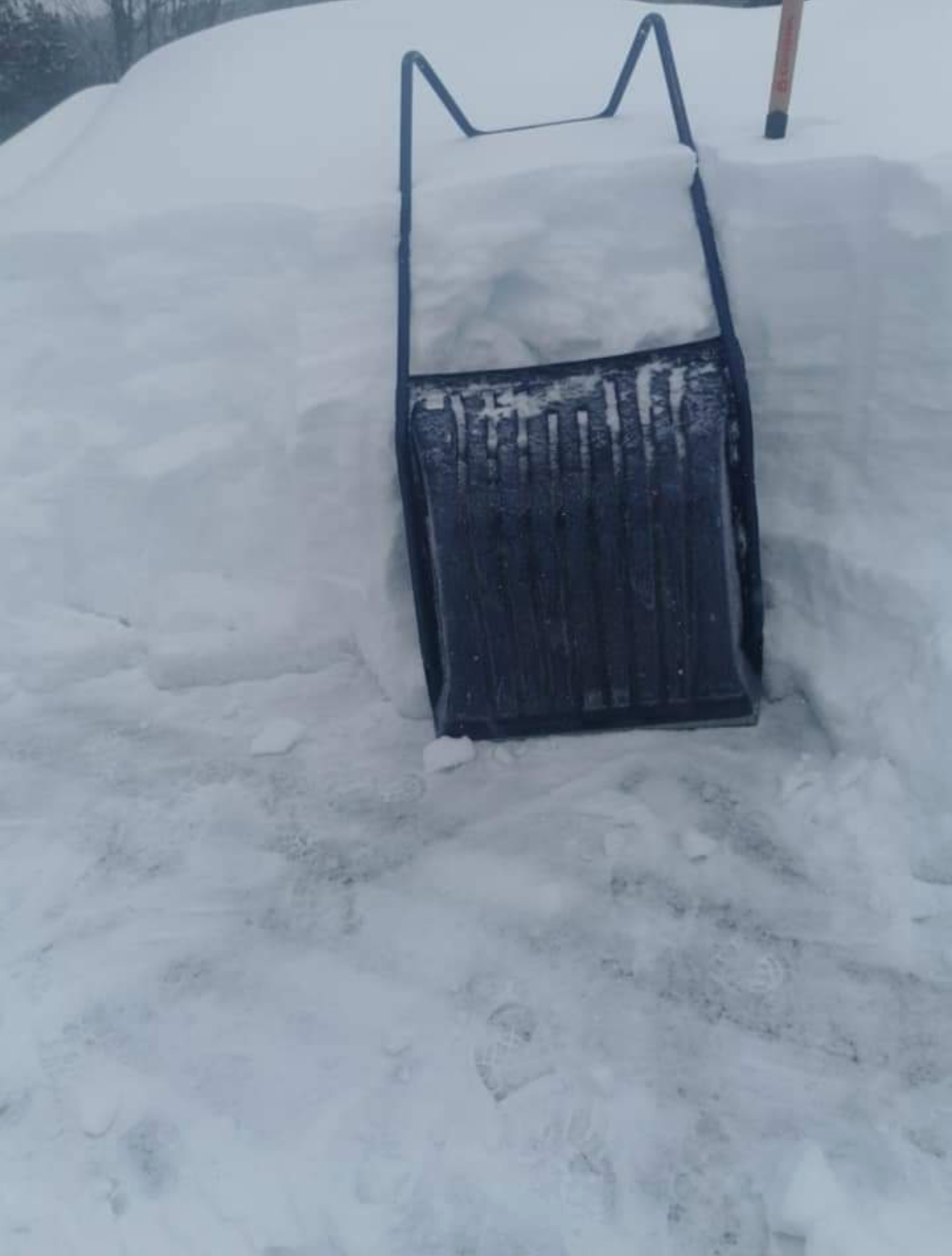 Une pelle à neige est posée au sommet d'un tas de neige