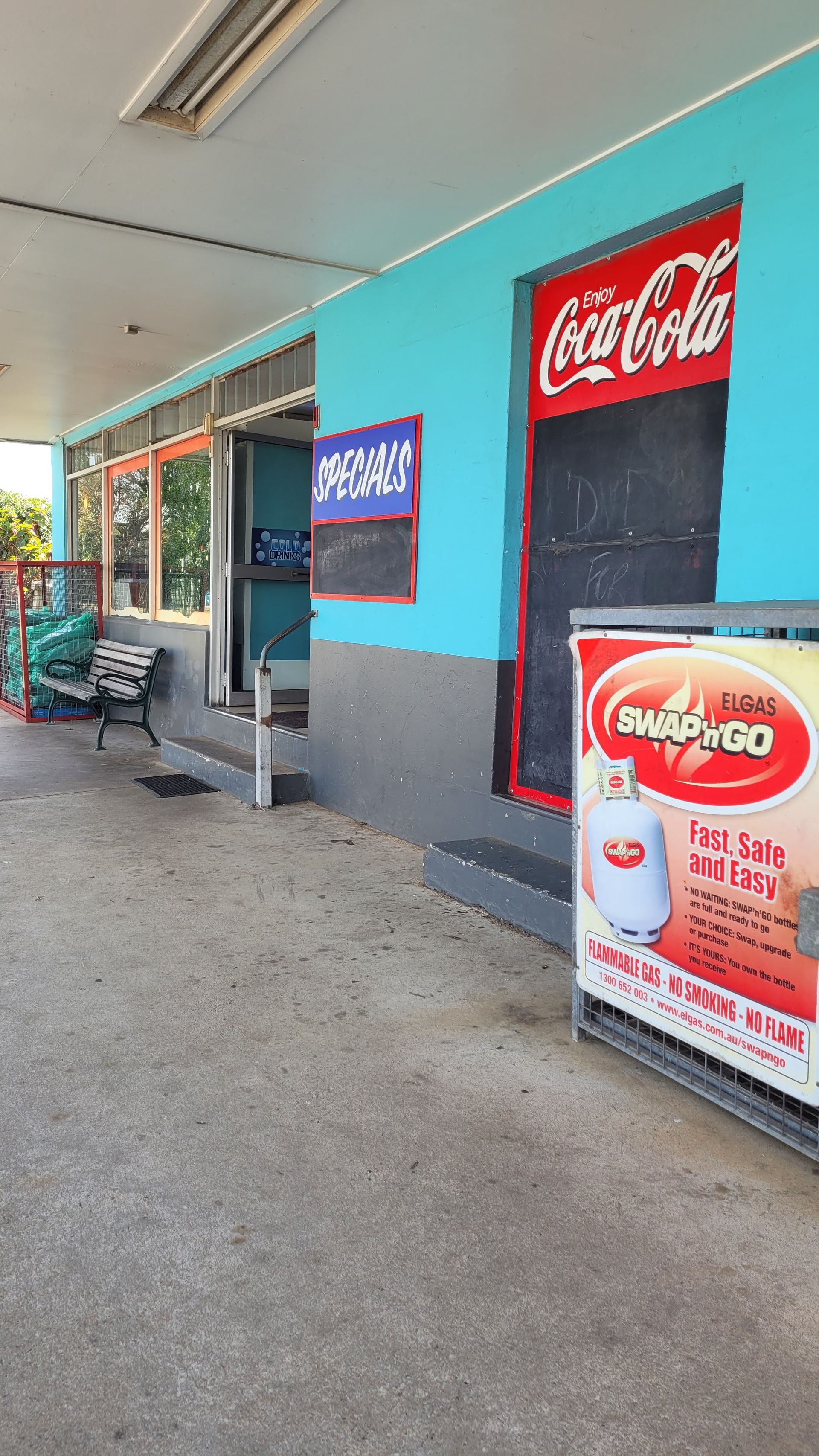 A Coca Cola Sign is on the Side of a Building — West End Cash Store In Proserpine, QLD