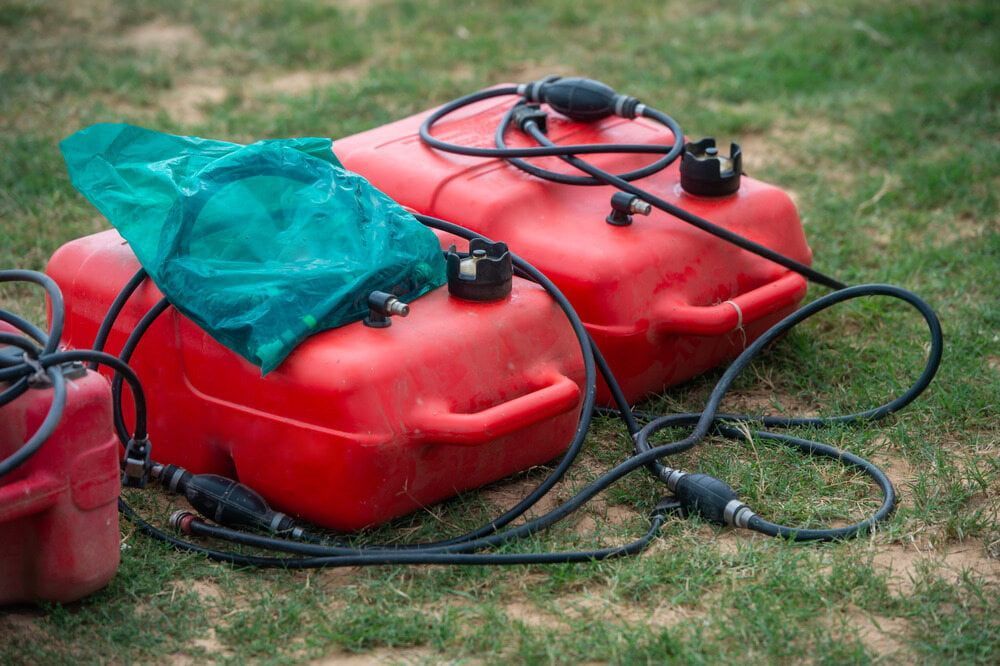 Two Red Gas Cans Are Sitting on Top of Each Other on the Grass — West End Cash Store In Proserpine, QLD