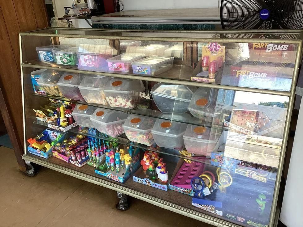 A Glass Display Case Filled With Lots of Candy and Toys — West End Cash Store In Proserpine, QLD