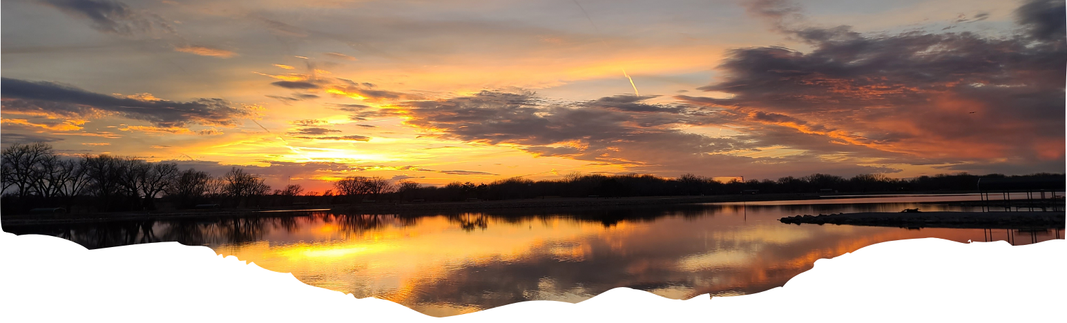 A sunset over a lake with trees in the background
