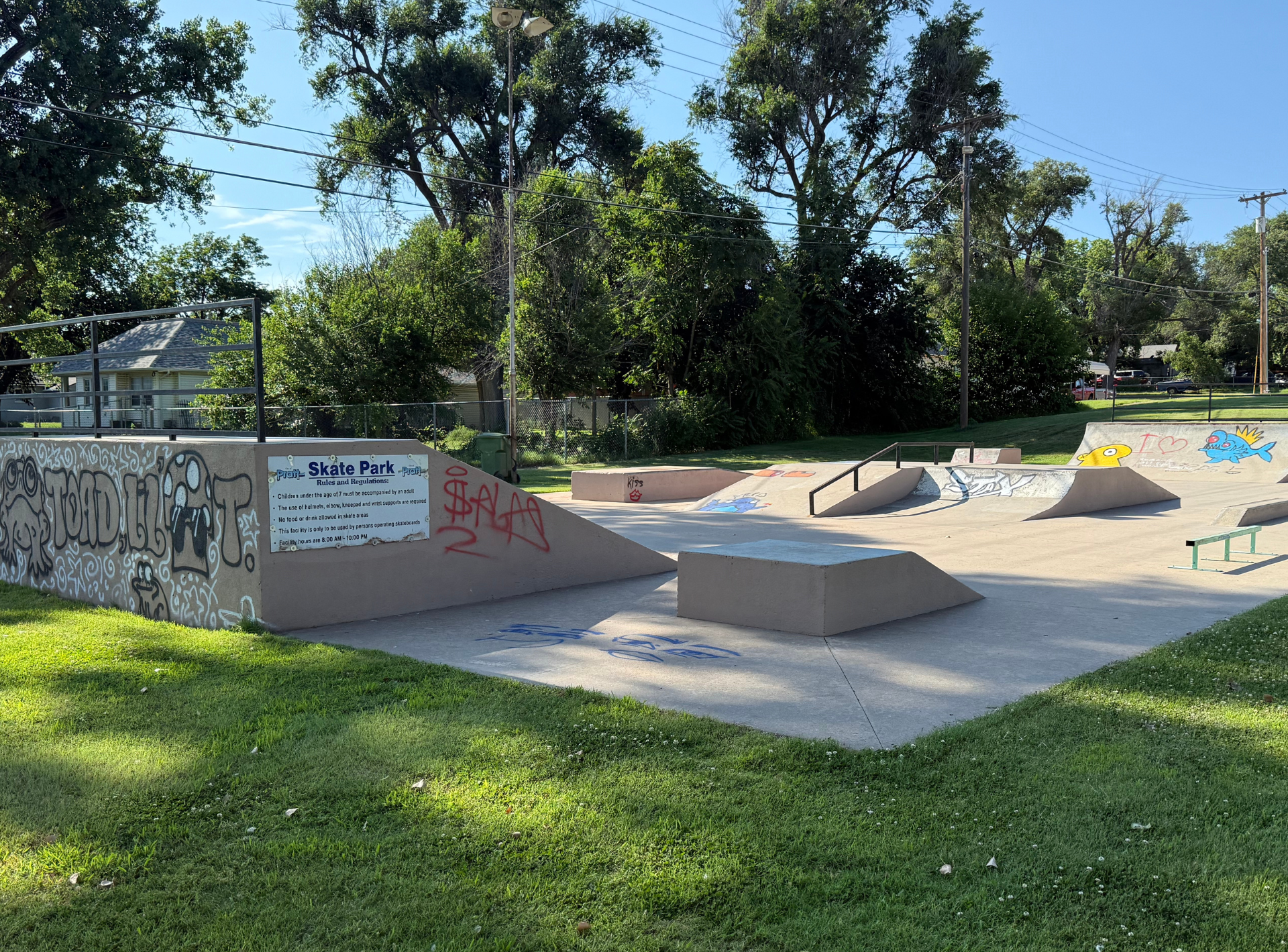 A skate park in a park with graffiti on the wall