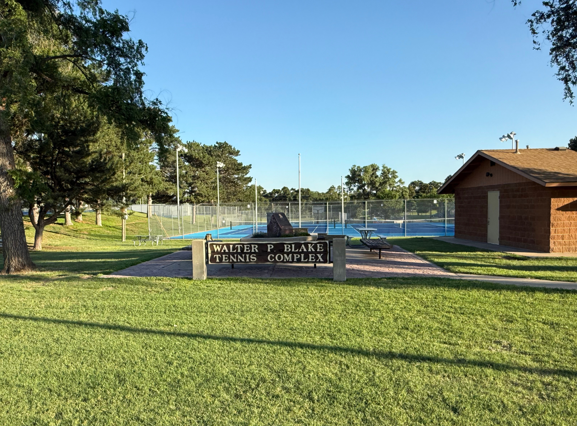 A park with a sign that says ' saliba f. blair tennis courts ' on it