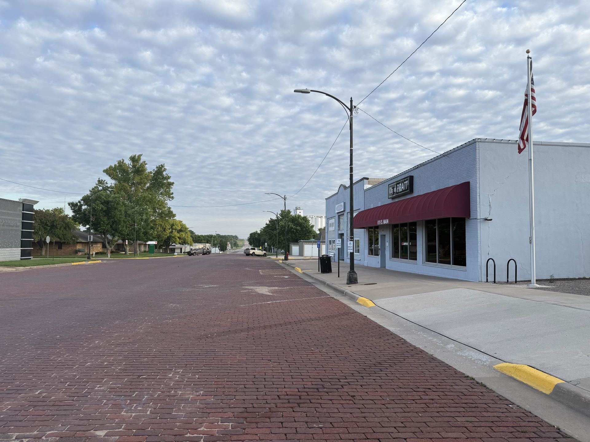 A red brick street with a white building on the right