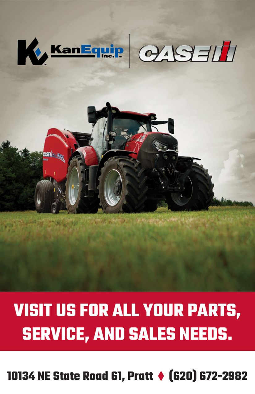A red and black tractor is parked in a grassy field.
