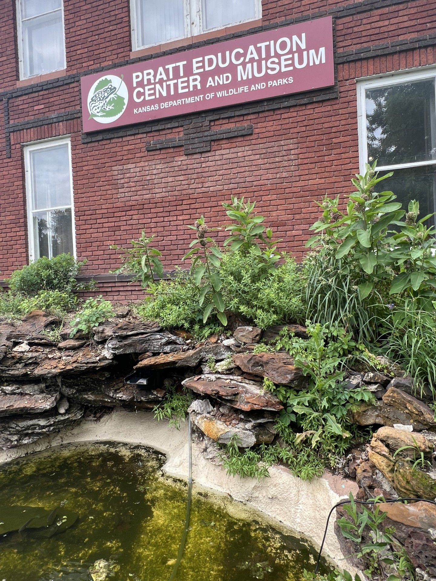 The pratt education center and museum has a pond in front of it.