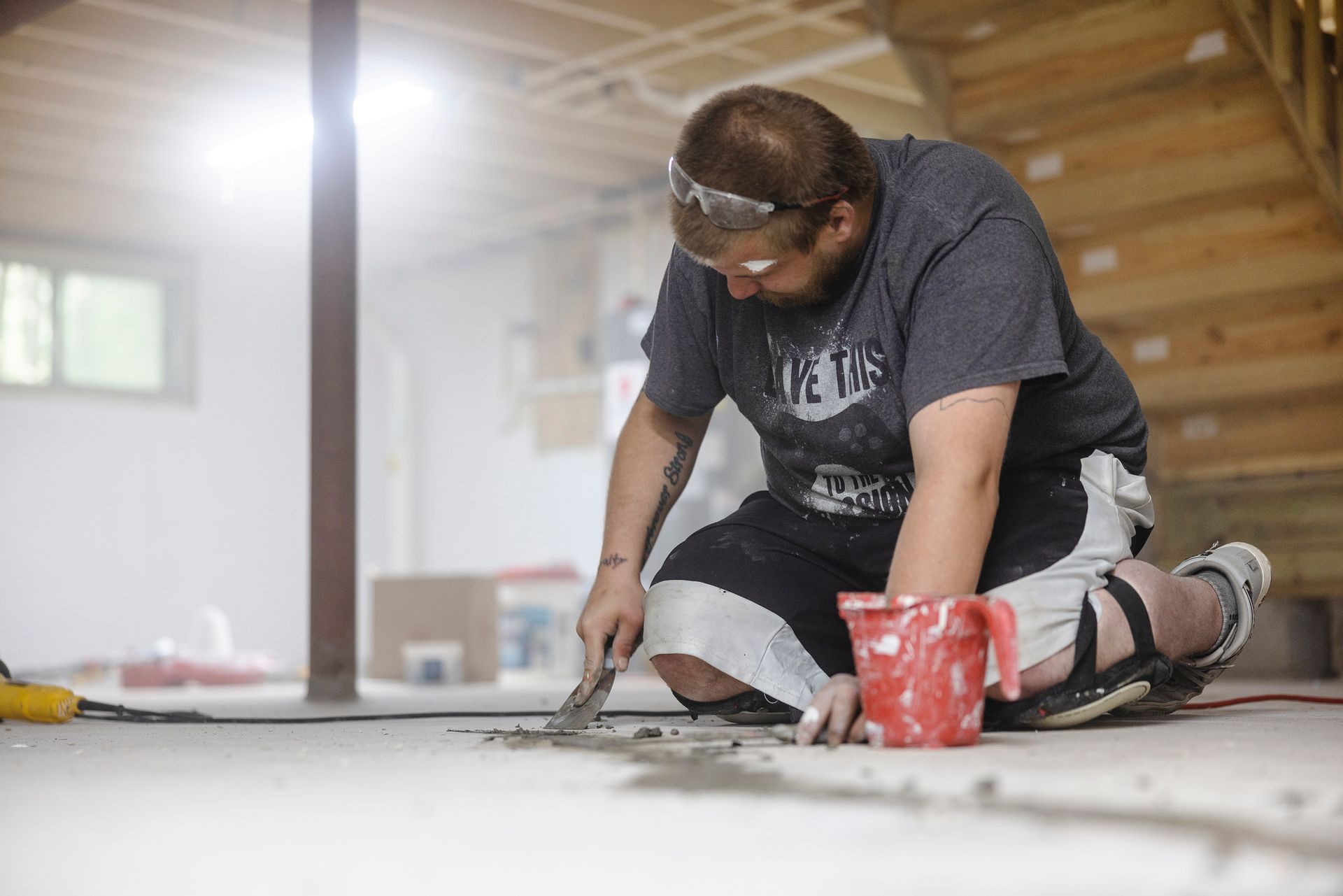 Worker sealing basement floor cracks for residential waterproofing