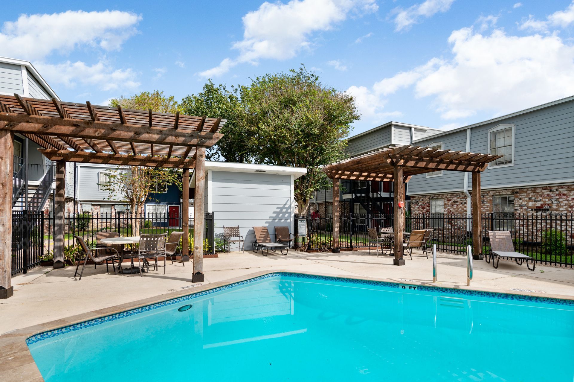 Swimming pool with pergolas and seating area at an apartment complex.