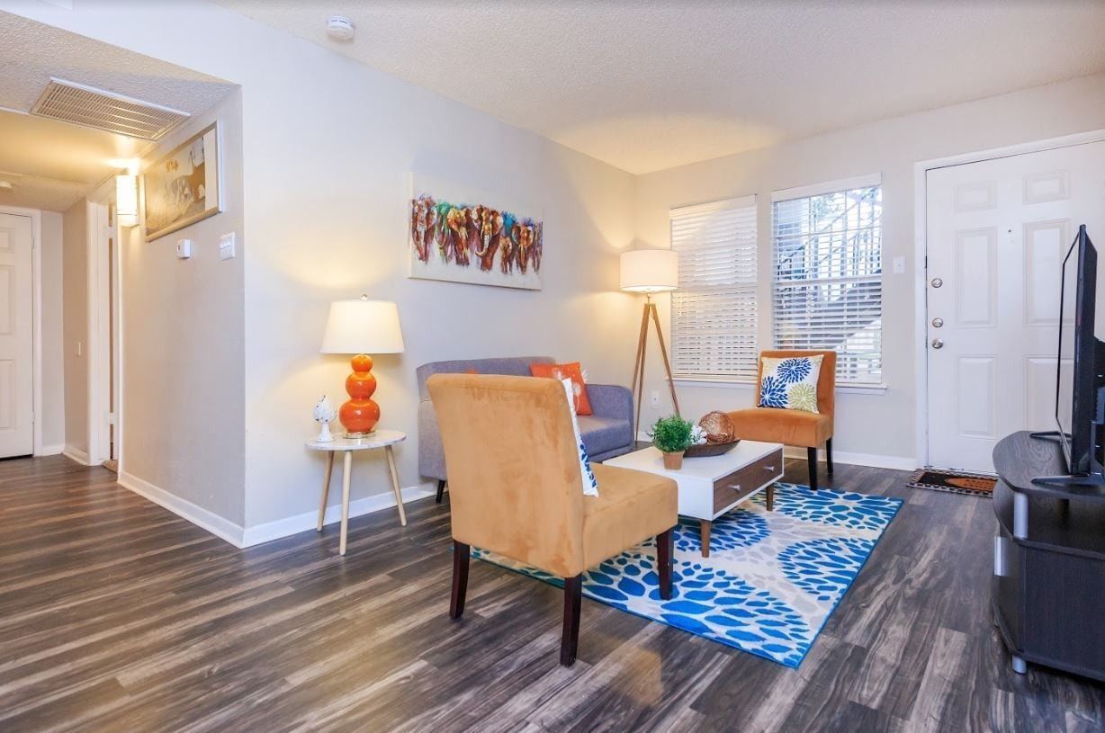 Living room with orange chairs, blue rug, and modern decor.