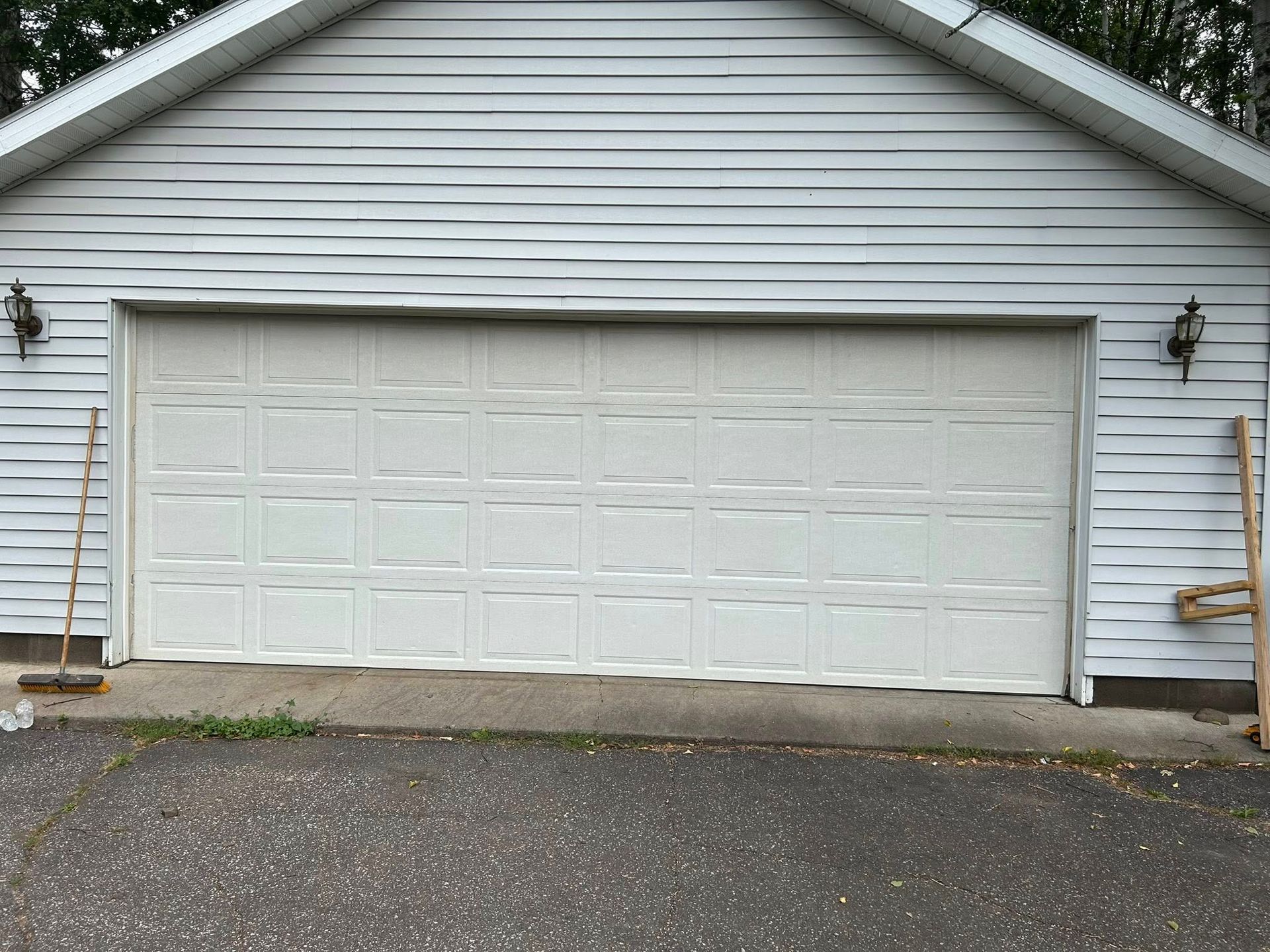 White garage door, horizontal panel design, under gabled roof, two lights on sides.
