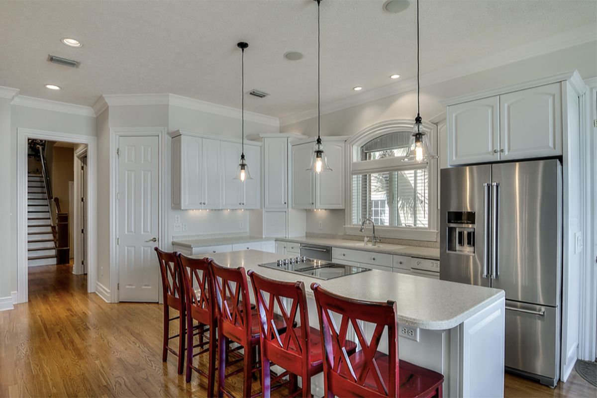 Une cuisine avec des armoires blanches et des appareils électroménagers en acier inoxydable