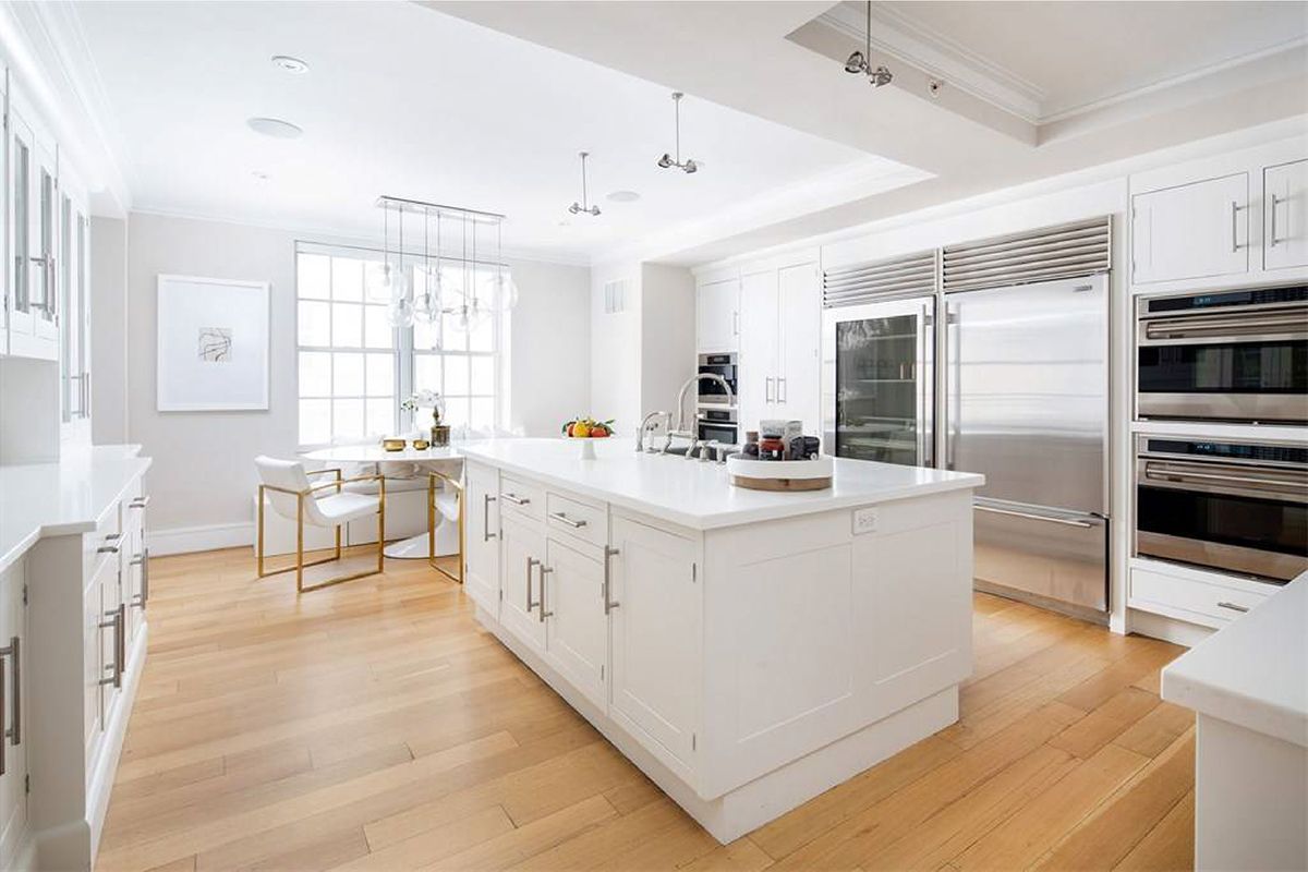 Une grande cuisine avec des armoires blanches et des appareils en acier inoxydable.