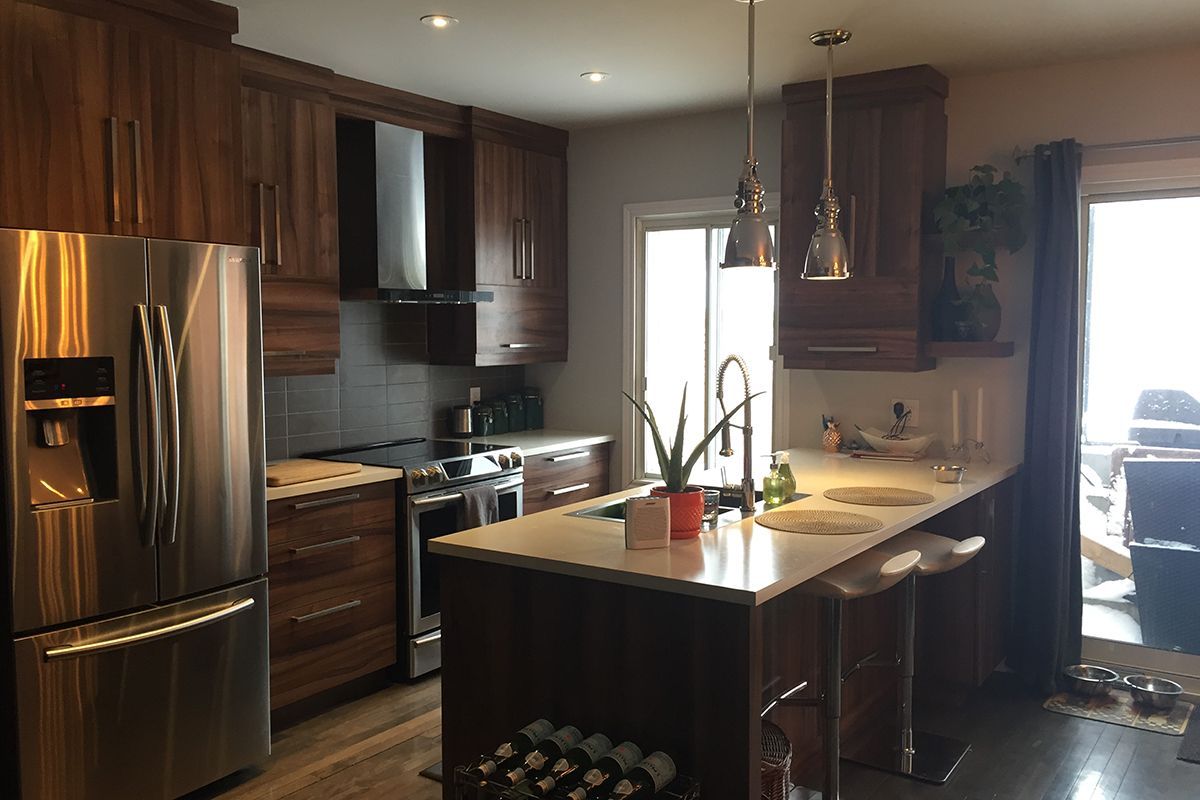 Une cuisine avec électroménagers en acier inoxydable et armoires en bois.