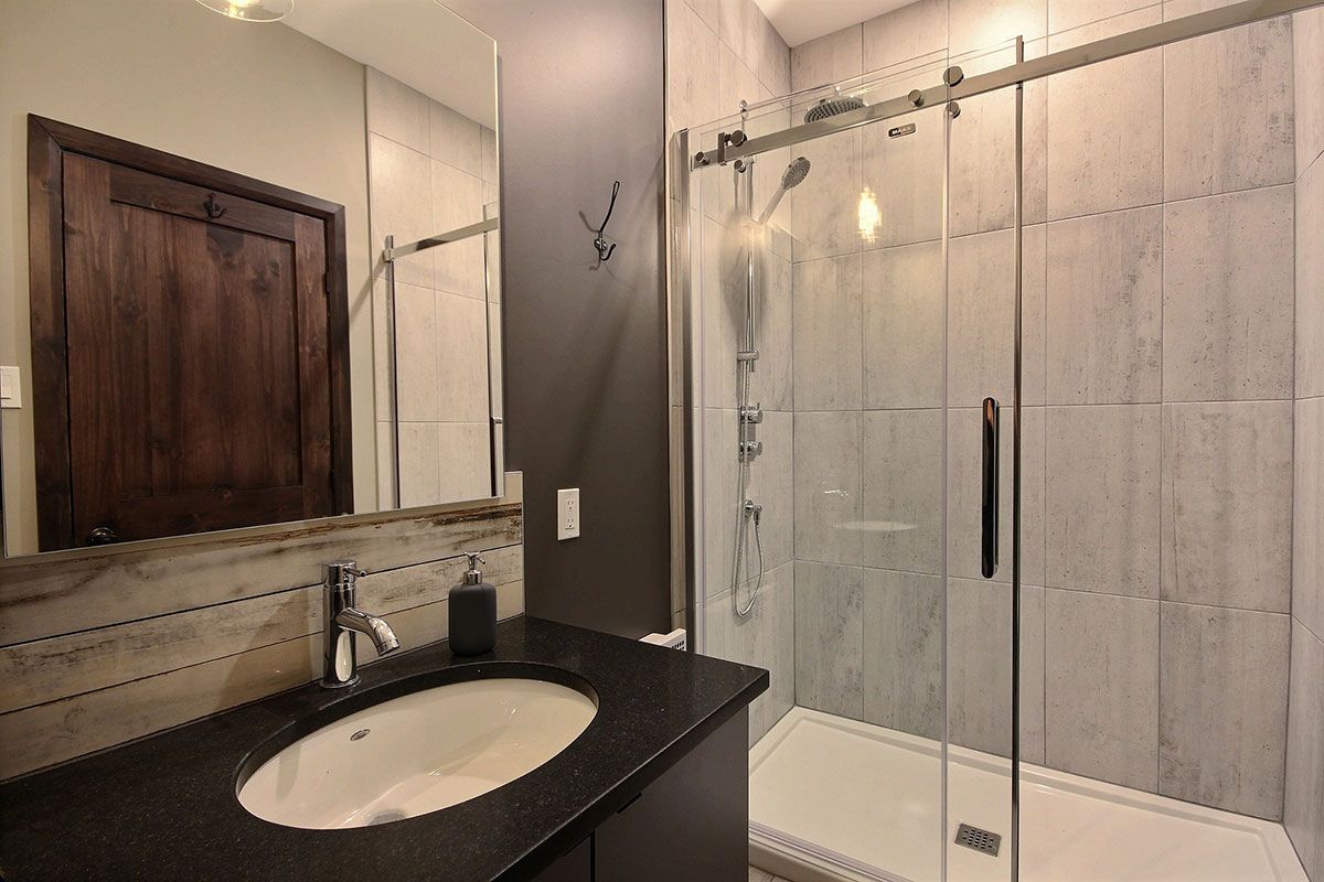 Une salle de bain avec lavabo, miroir et cabine de douche.