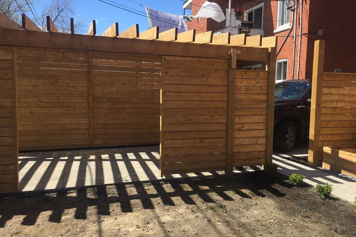 Une clôture en bois avec une voiture garée devant.