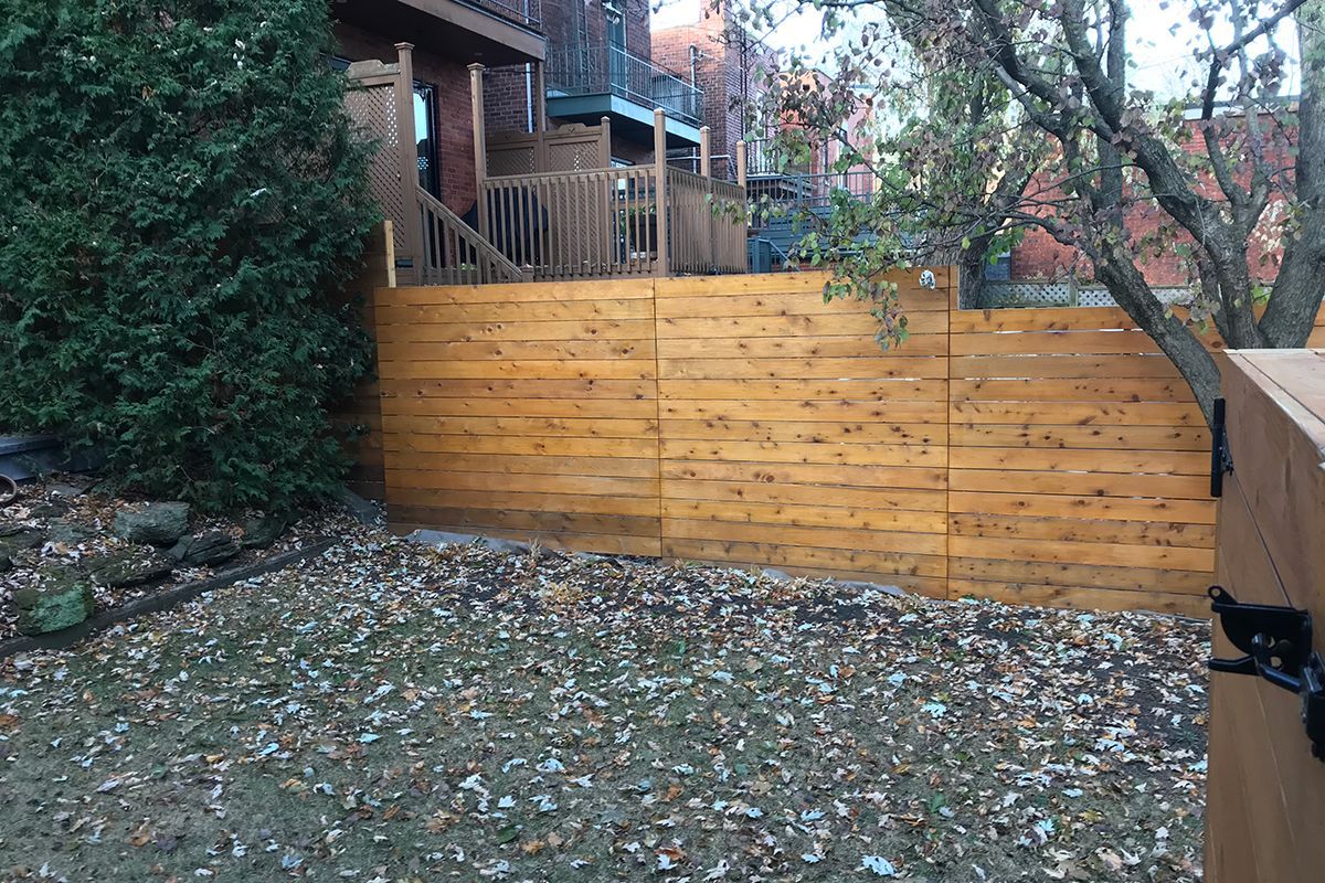 Une clôture en bois se trouve dans l'arrière-cour d'une maison.