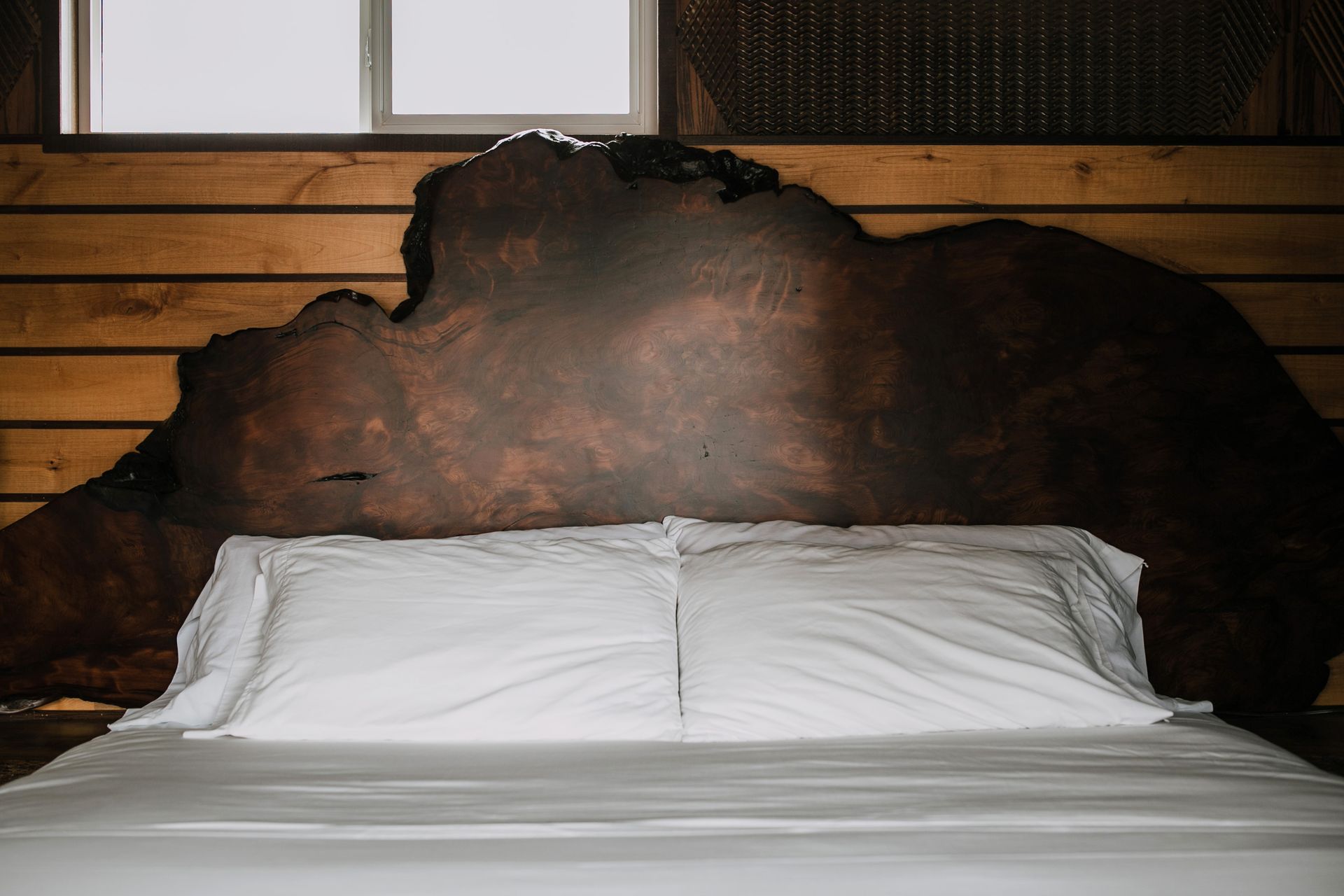 A bed with white sheets and a wooden headboard in a bedroom.