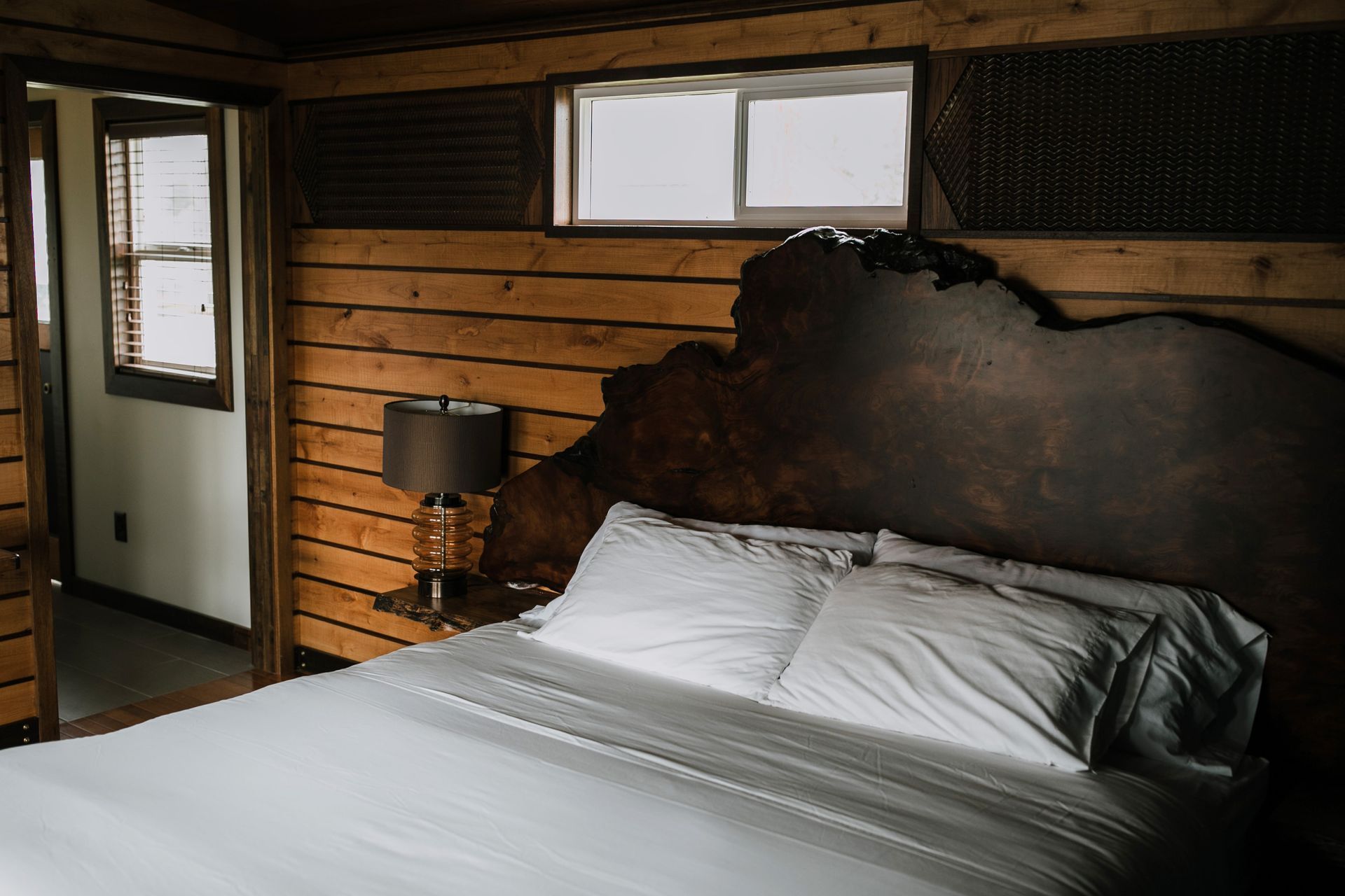 A bed with white sheets and a wooden headboard in a bedroom.