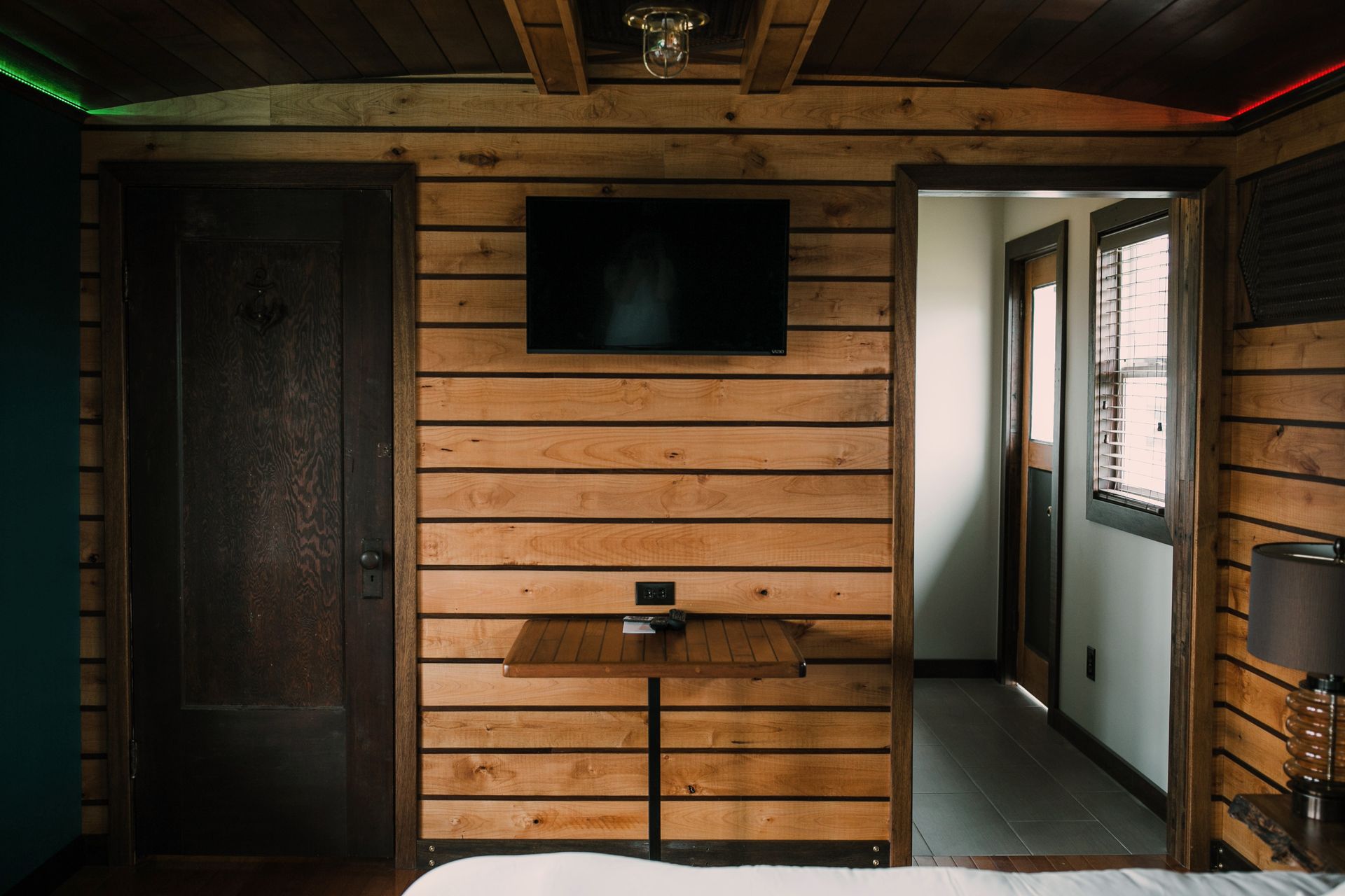 A bedroom with a wooden wall and a flat screen tv on the wall.