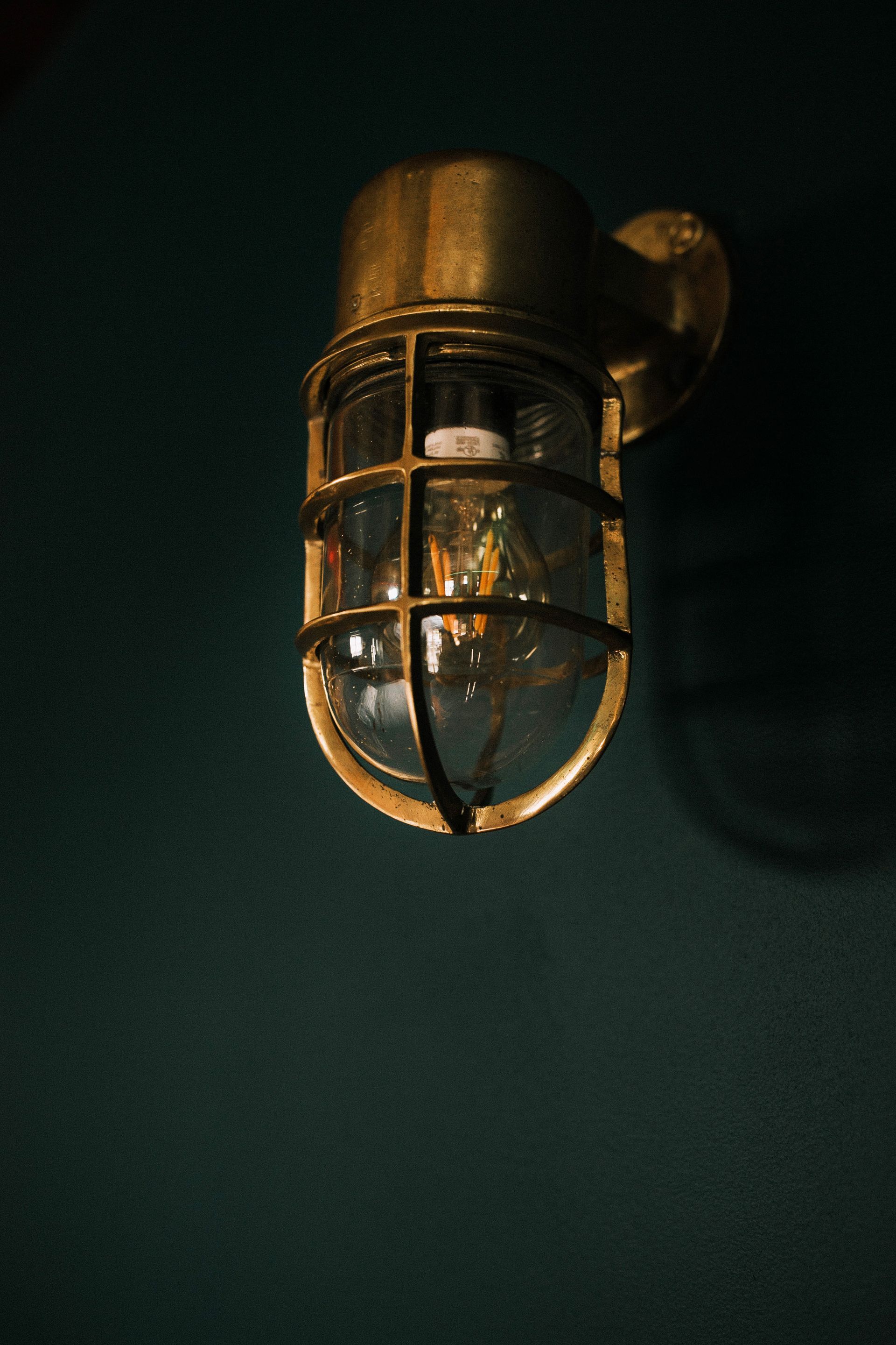 A close up of a brass light fixture with a light inside of it.