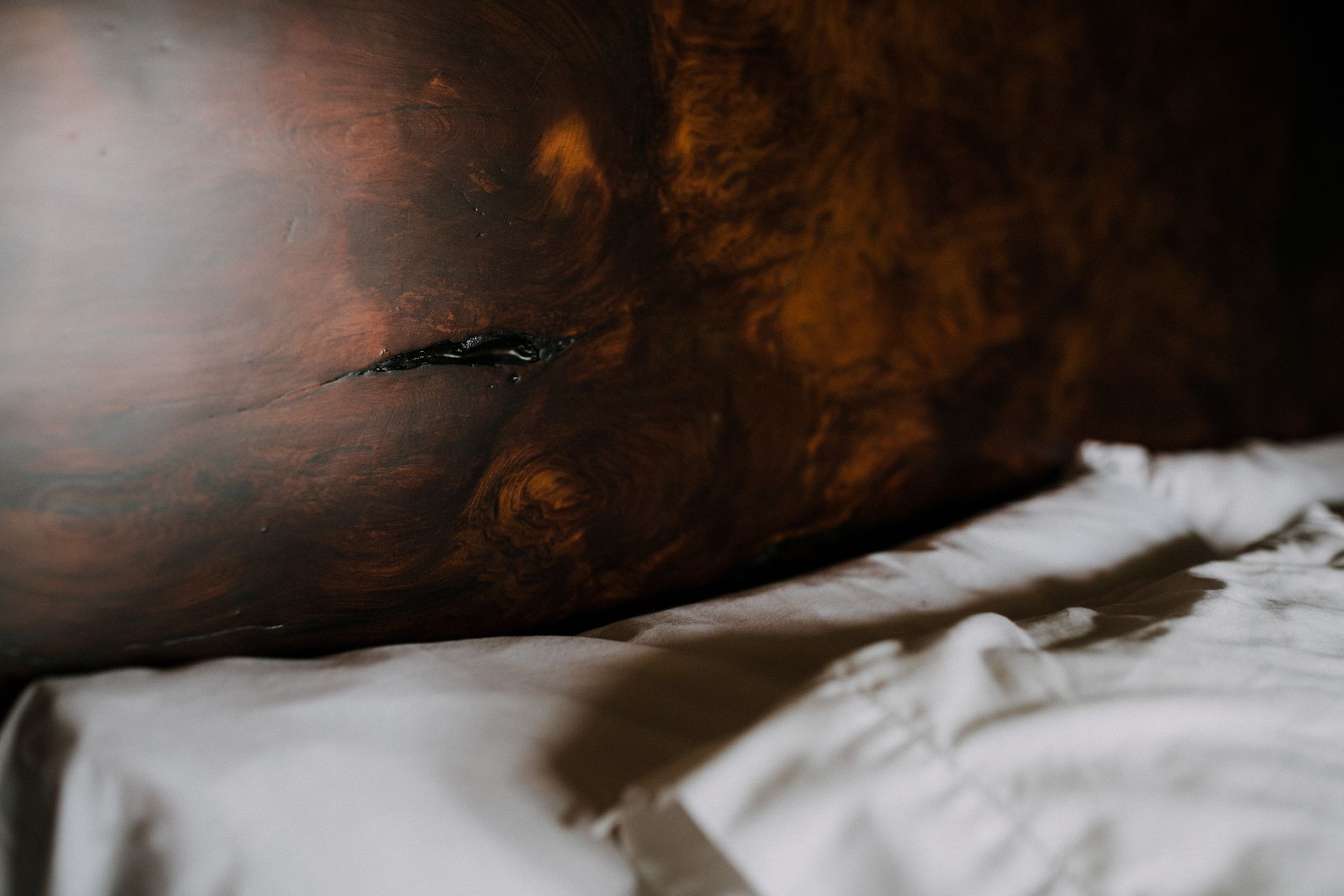 A person is laying on a bed with a painting on the wall behind them.
