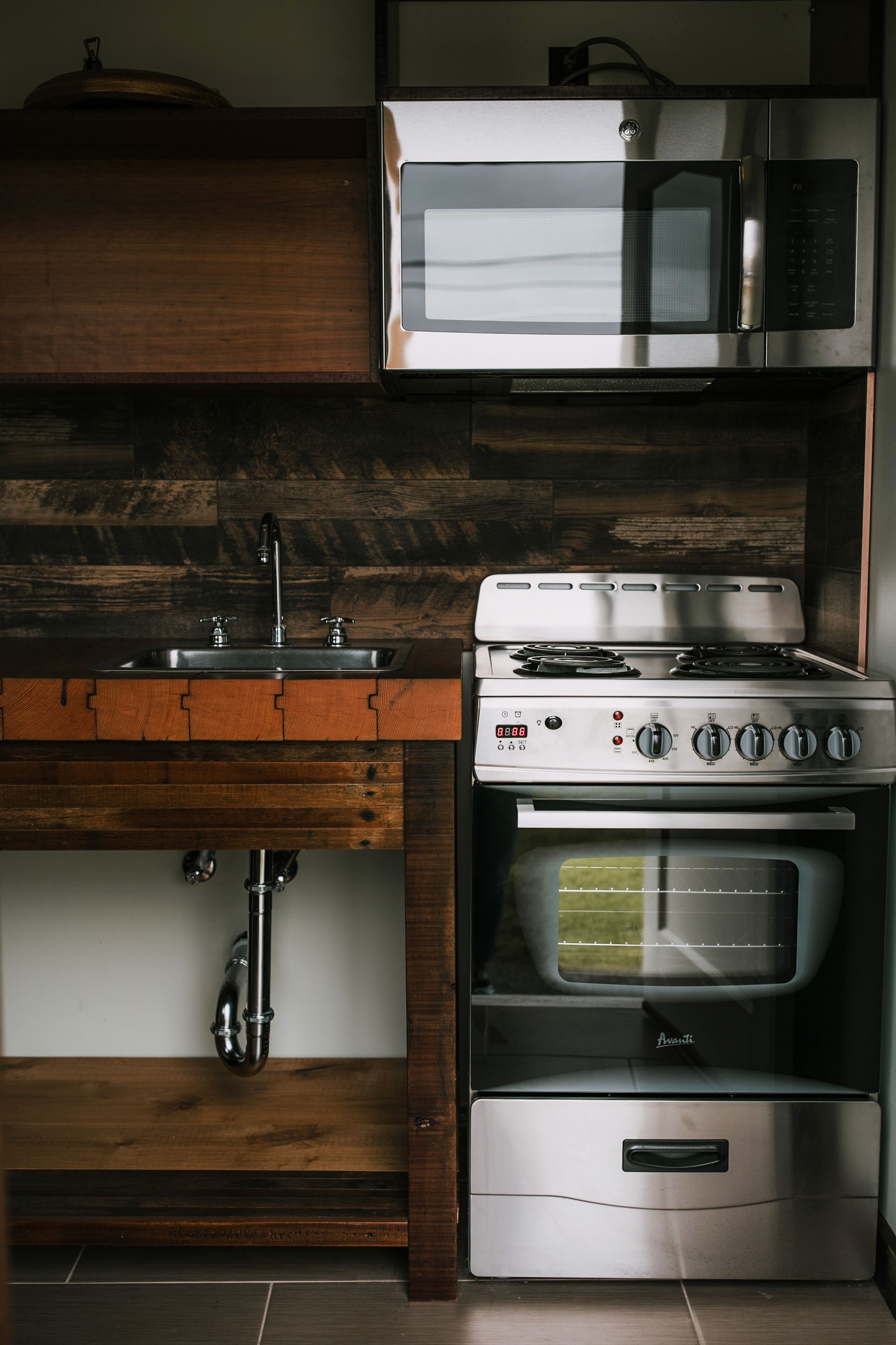 A kitchen with a stove , sink and microwave
