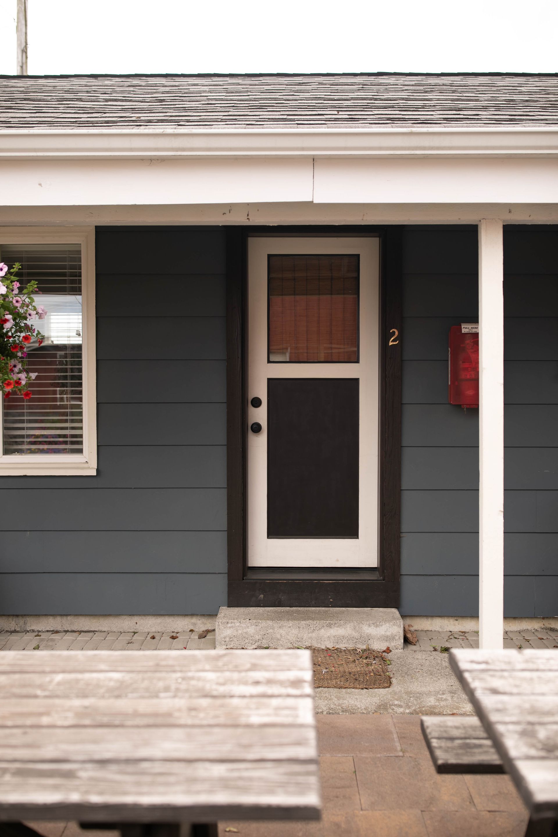 A blue house with a screen door and a picnic table in front of it
