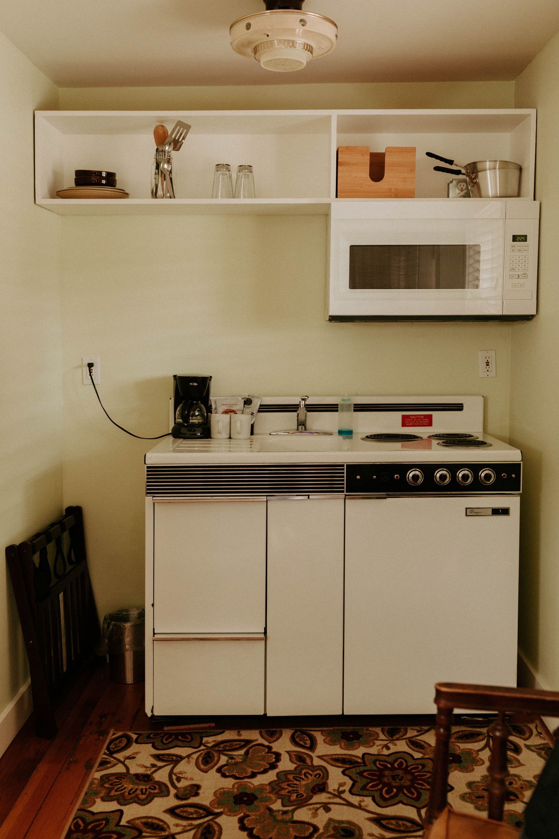 A small kitchen with a stove , sink and microwave