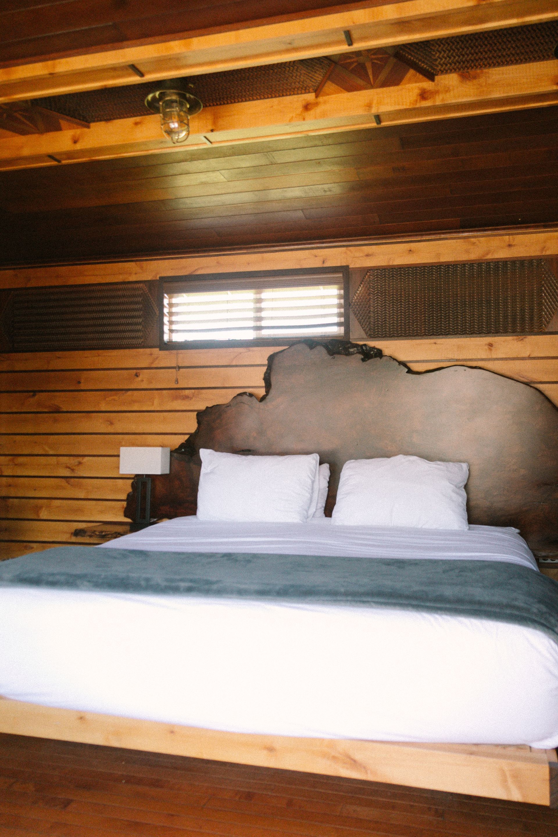 A bed with white sheets and a wooden headboard in a bedroom.