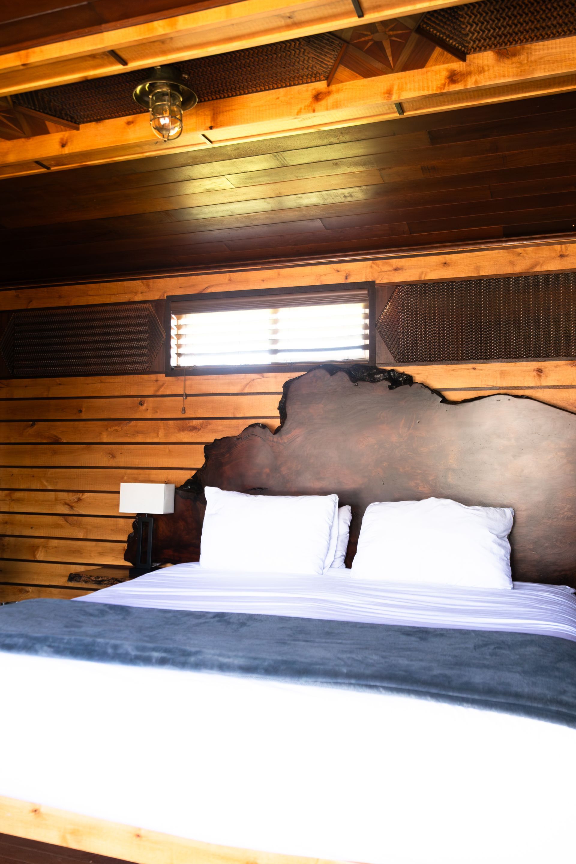 A bed with white sheets and a wooden headboard in a bedroom.