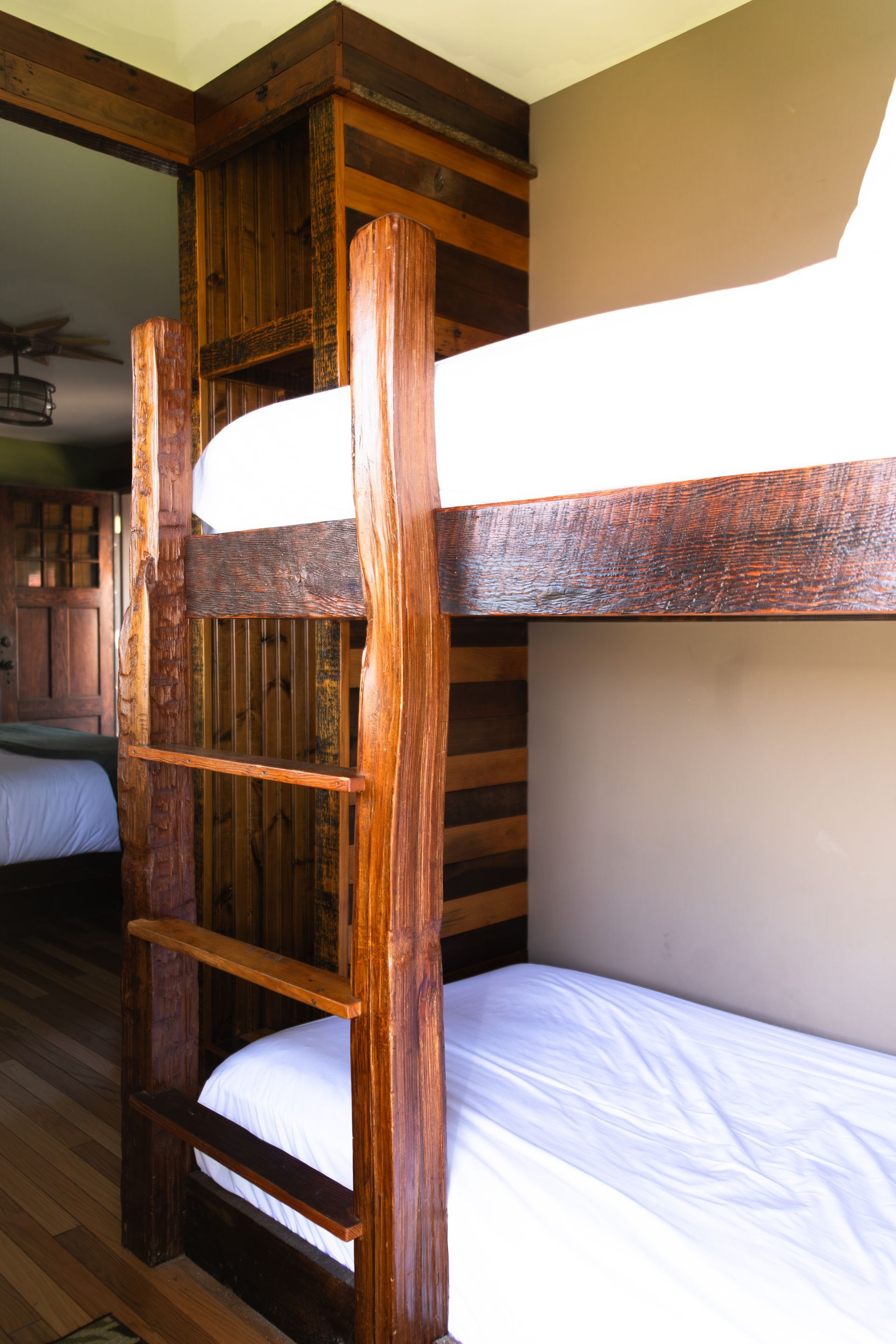 A bedroom with a bunk bed and a bed with white sheets.